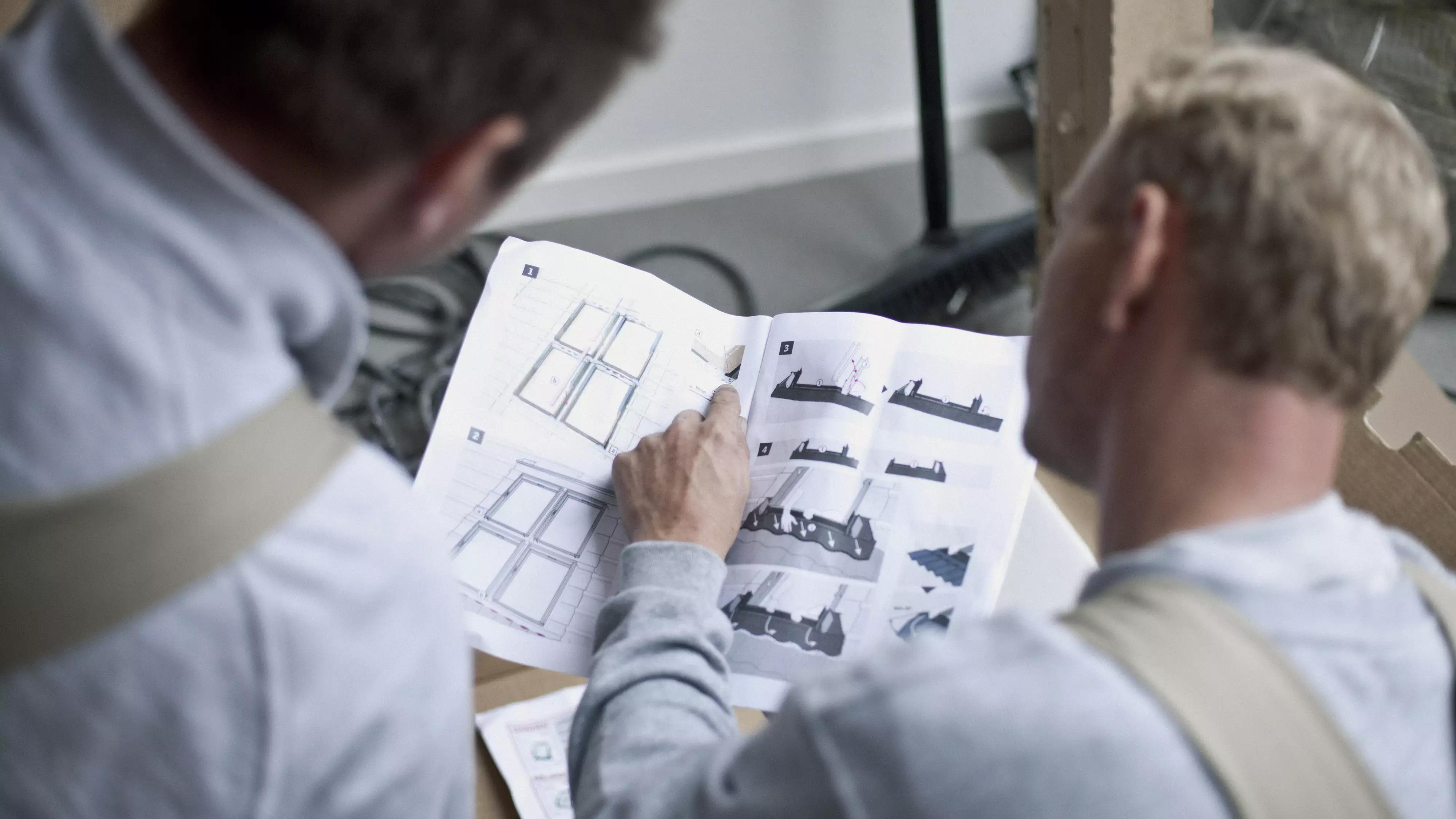 Handwerker studieren eine Einbauanleitung für den Einbau von VELUX Dachfenstern